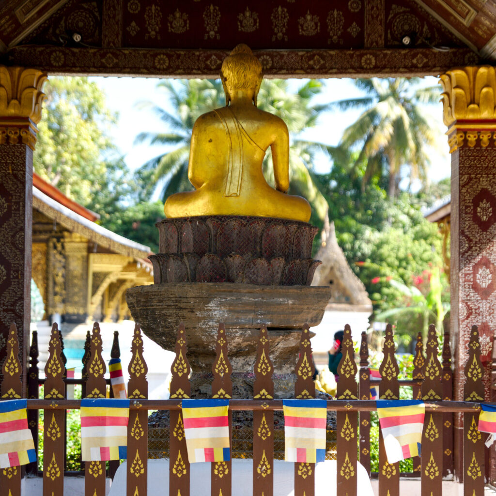 Golden Buddha behind a prayer-flag fence, Laos: Luang Prabang to Vientiane