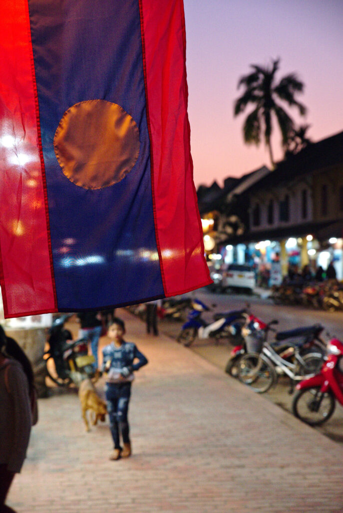 Lao flag over the old town street at dusk, Laos: Luang Prabang to Vientiane