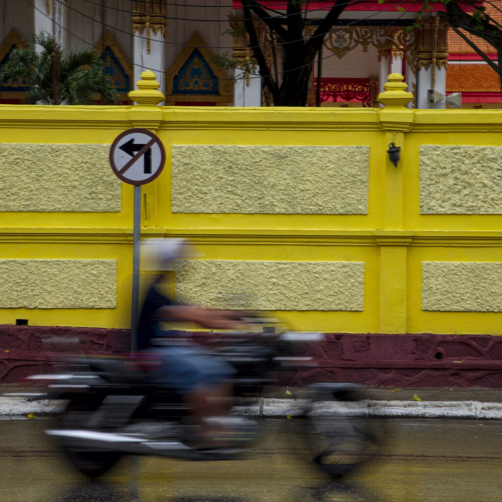 Moped blur past a yellow wall, Old Town, Phuket