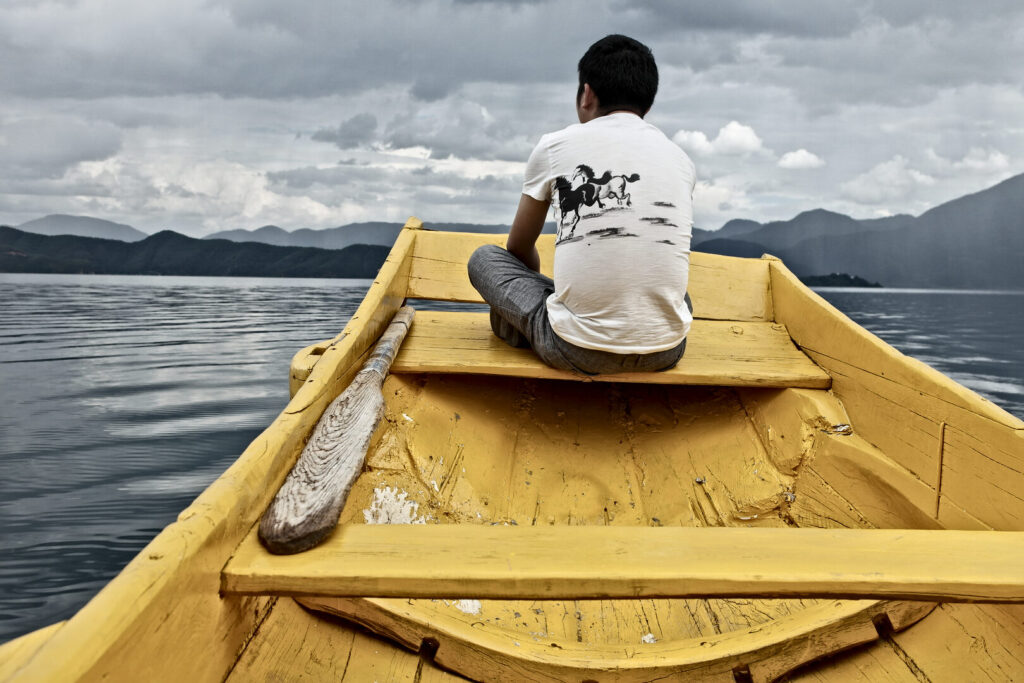 Boatman in a yellow dugout, Lugu Lake, Yunnan: Kunming to Shangri-La